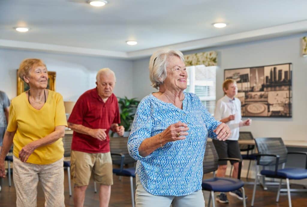 Group of older adults dancing together in a senior living class