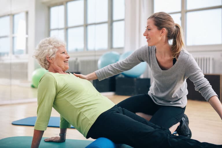 Fitness instructor helping an older woman with a pose