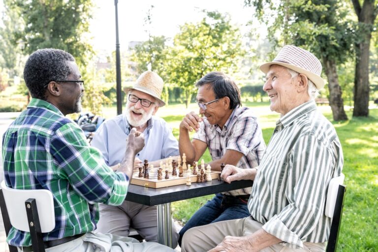A group of seniors happily playing chess outdoors