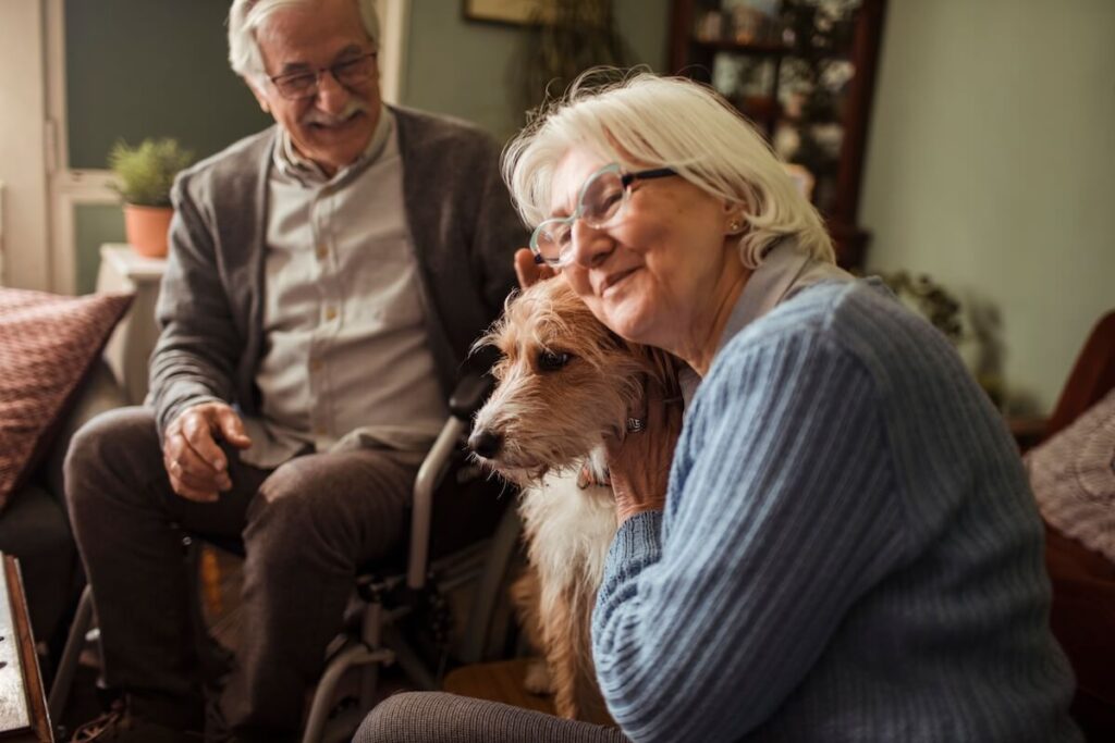 A couple of older adults interacting with a cute dog