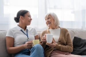 Happy older woman talking to a younger caregiver about senior living