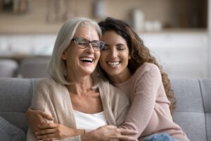 Smiling woman hugging her elderly mother with glasses